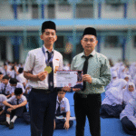 Muhammad Azzam Nurhaidi dengan bangga memegang medali dan piagam penghargaan